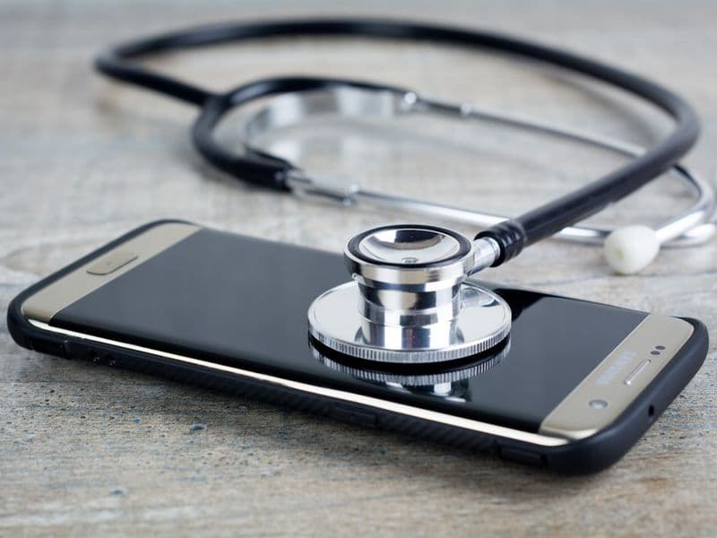 smartphone com estetoscópio em cima simbolizando check-up digital e organização de exames preventivos
